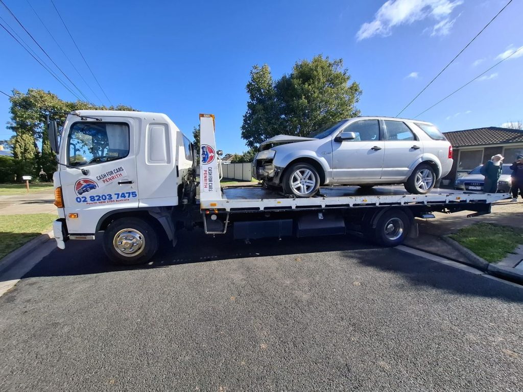 Silver Ford Territory with front-end accident damage on the Cash For Cars Penrith tilt-tray truck
