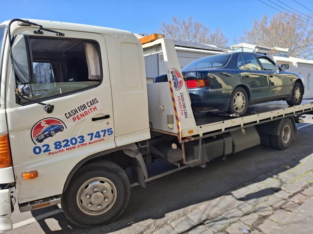 Dark green Toyota Camry sedan loaded on the Cash For Cars Penrith tilt-tray truck