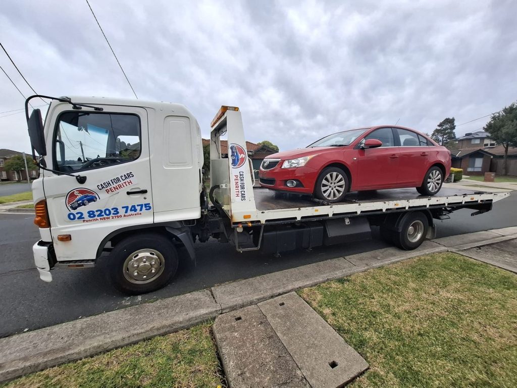 Red Holden Cruze sedan loaded on the Cash For Cars Penrith tilt-tray truck