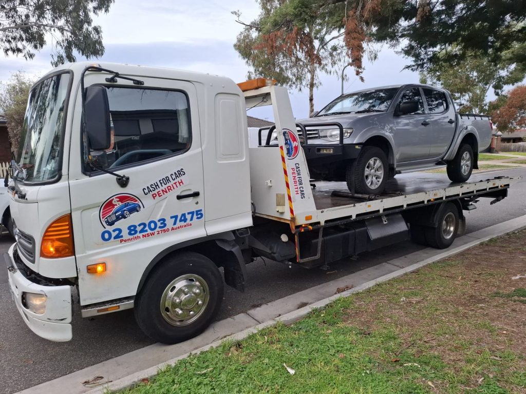 Silver Mitsubishi Triton dual-cab ute with bull bar on the Cash For Cars Penrith tilt-tray truck