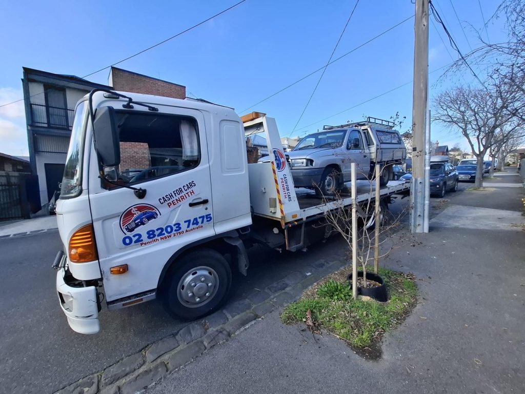 Silver single-cab ute with canopy loaded on the Cash For Cars Penrith tilt-tray truck