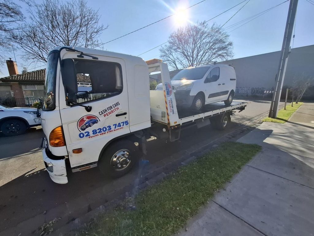 White compact van on the Cash For Cars Penrith tilt-tray truck