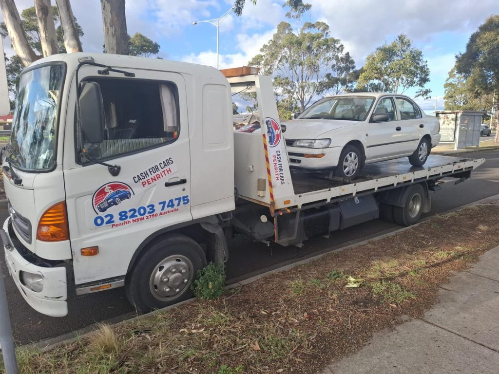 Older white Toyota Corolla sedan on the Cash For Cars Penrith tilt-tray truck