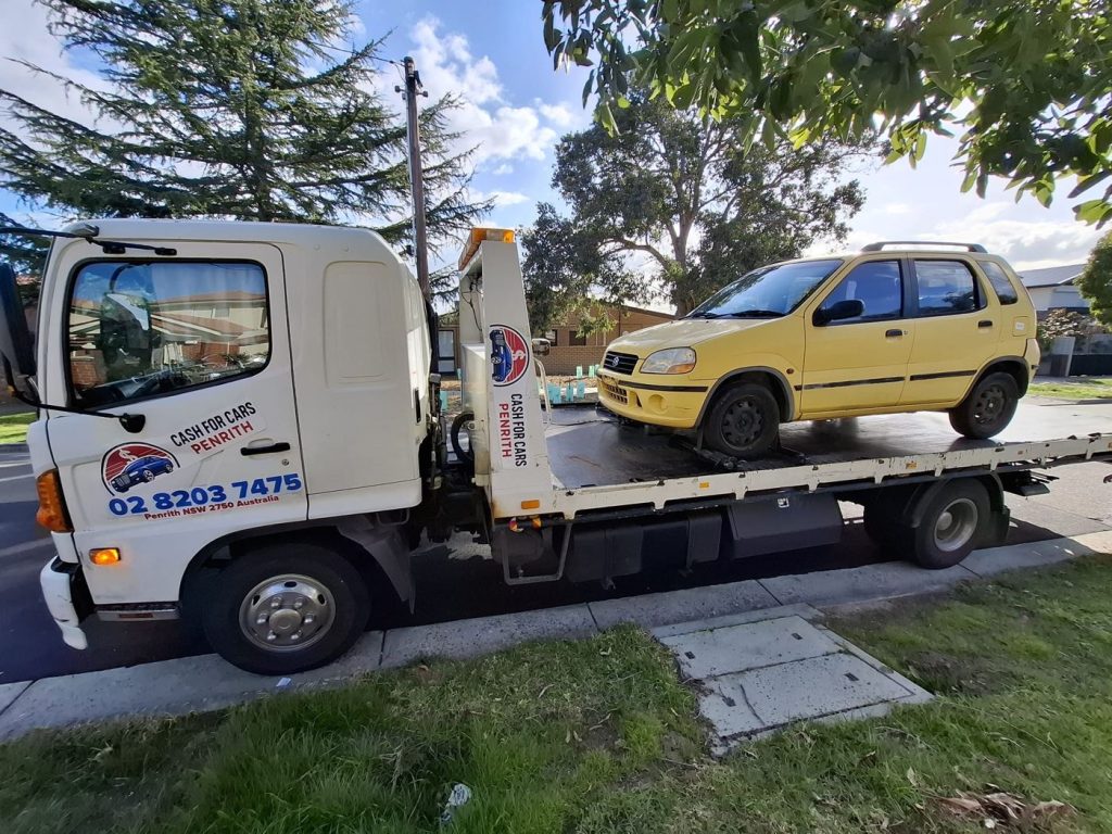 Yellow Suzuki Ignis hatchback on the Cash For Cars Penrith tilt-tray truck